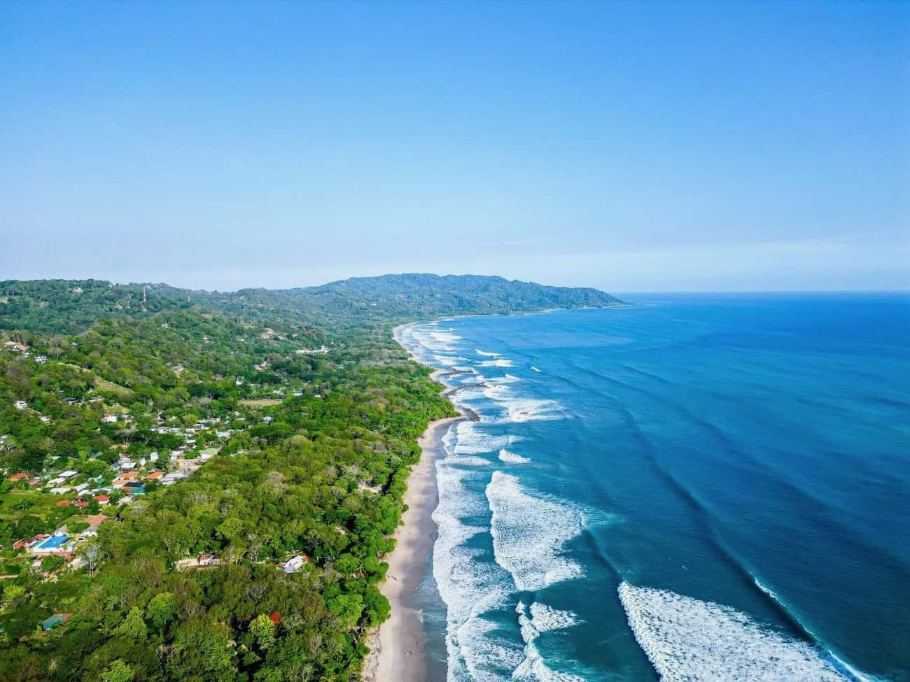 Aerial view of Playa Santa Teresa: Pacific Ocean waves meeting the jungle-covered coastline
