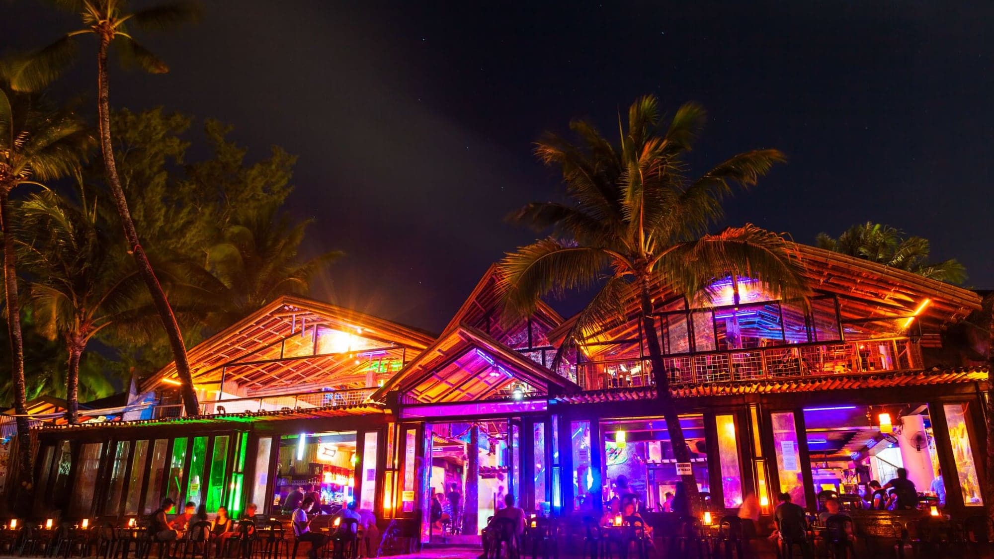 Santa Teresa beach club lit up at night, neon lights, palms