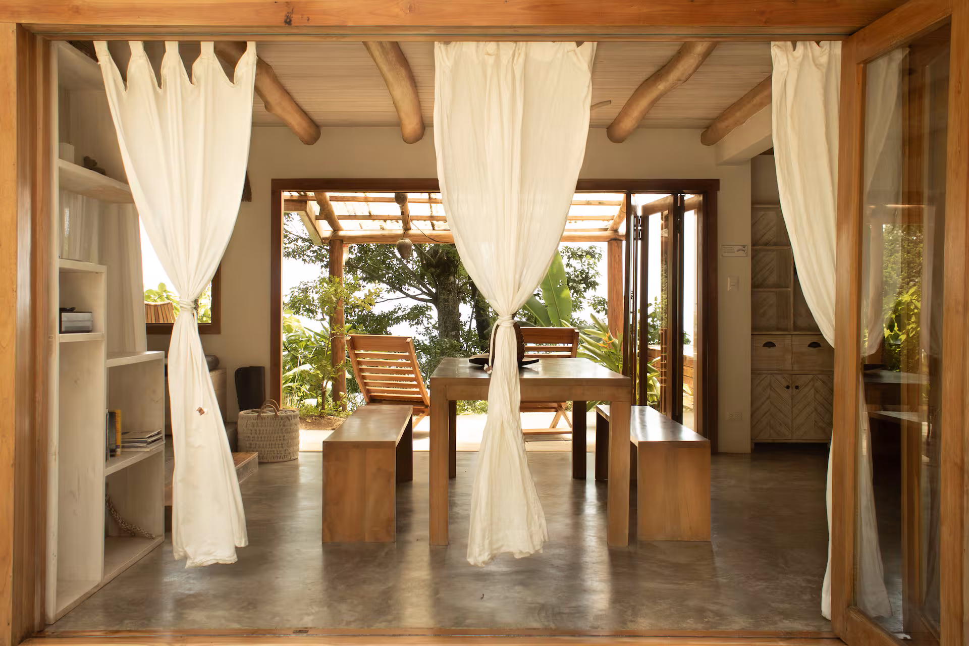 Living room with daybed and curtains framing a jungle view