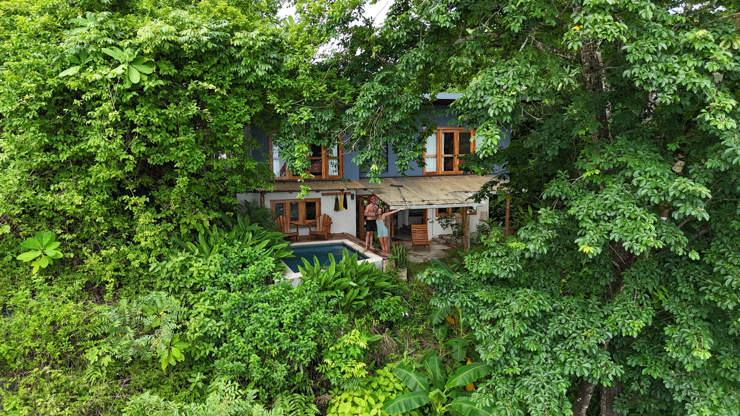 Aerial view of Casa Calyx nestled in dense Costa Rican jungle, infinity pool catching afternoon light